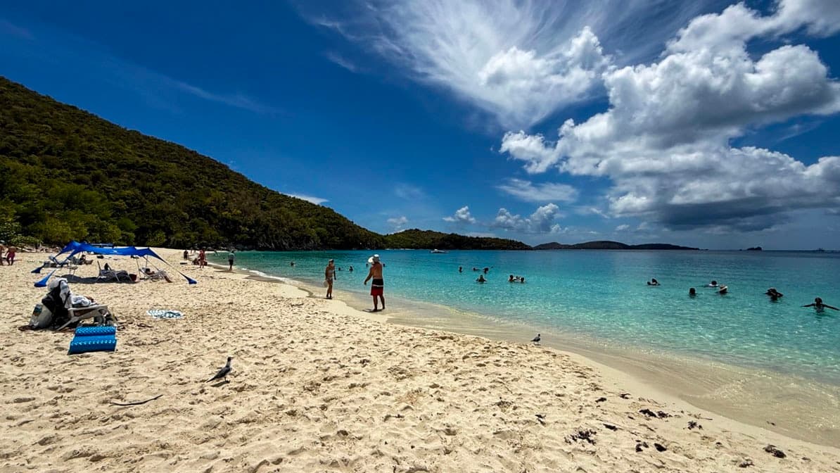 White sand, turquoise water, swimmers, and a cloud-filled sky at Trunk Bay on St. John.