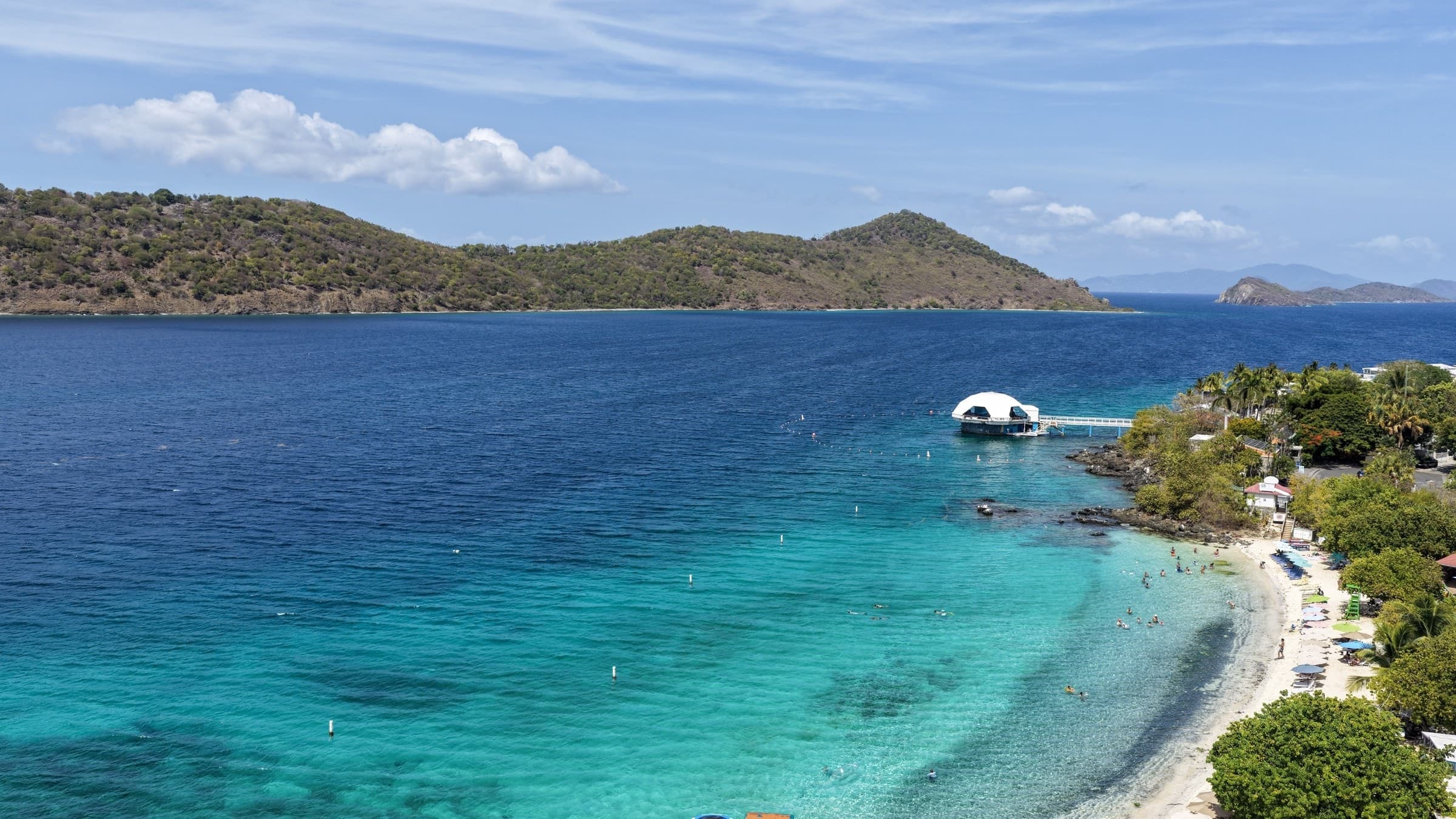 Aerial view of turquoise water and the curved shoreline at Coki Point Beach on St. Thomas.