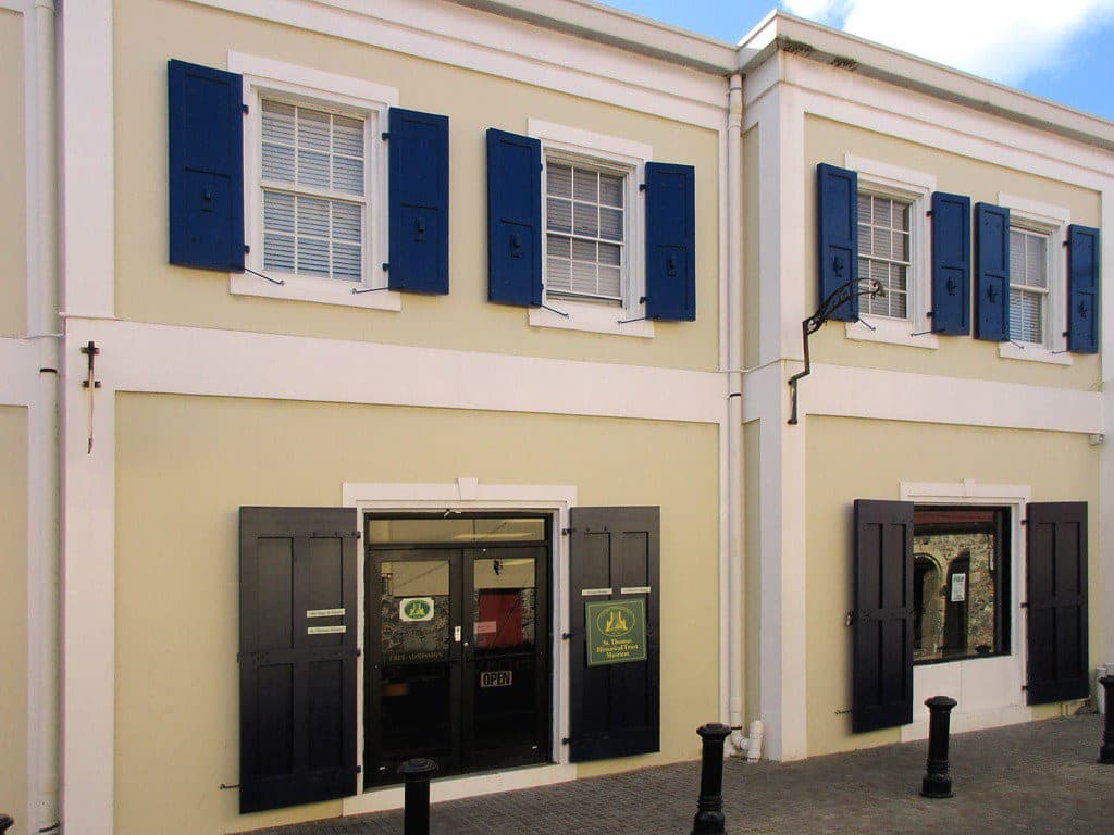 The St. Thomas Historical Trust Museum on Raadets Gade in Charlotte Amalie, its Danish colonial facade with blue shutters and the museum's own sign beside the entrance.