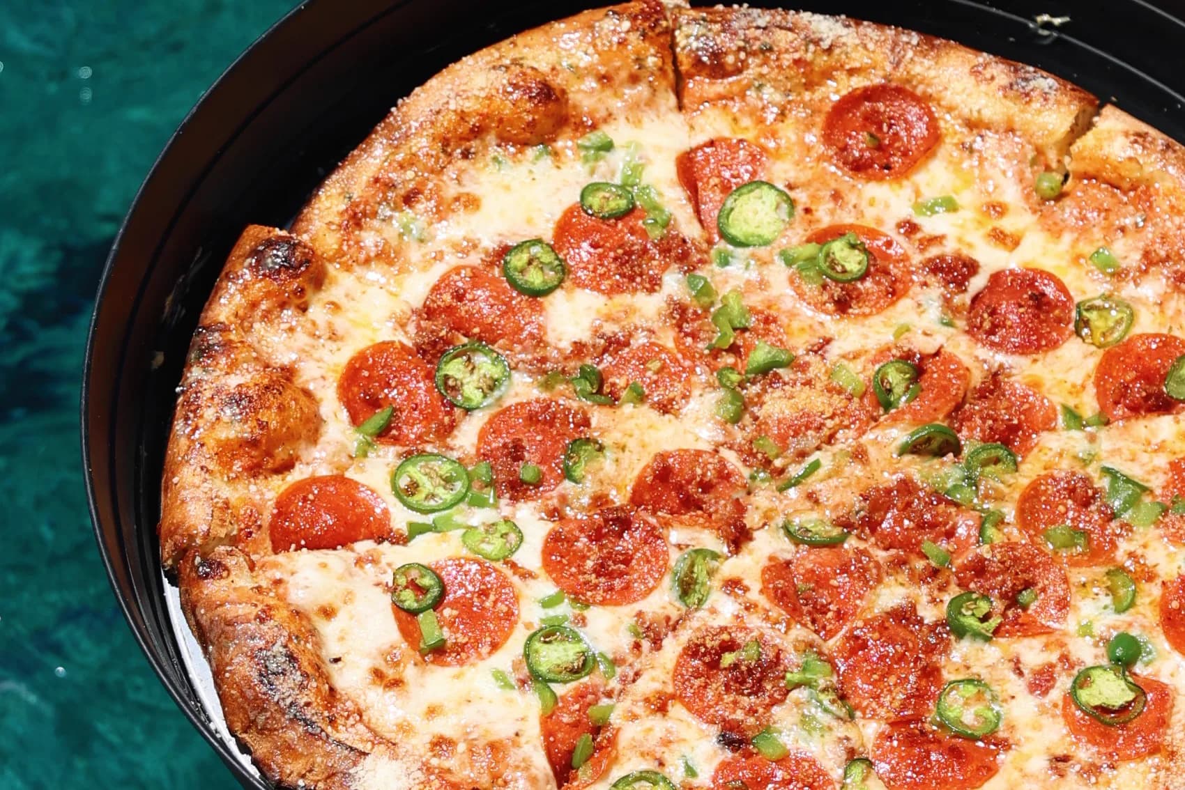 A Pizza Pi VI pizza photographed over the water.