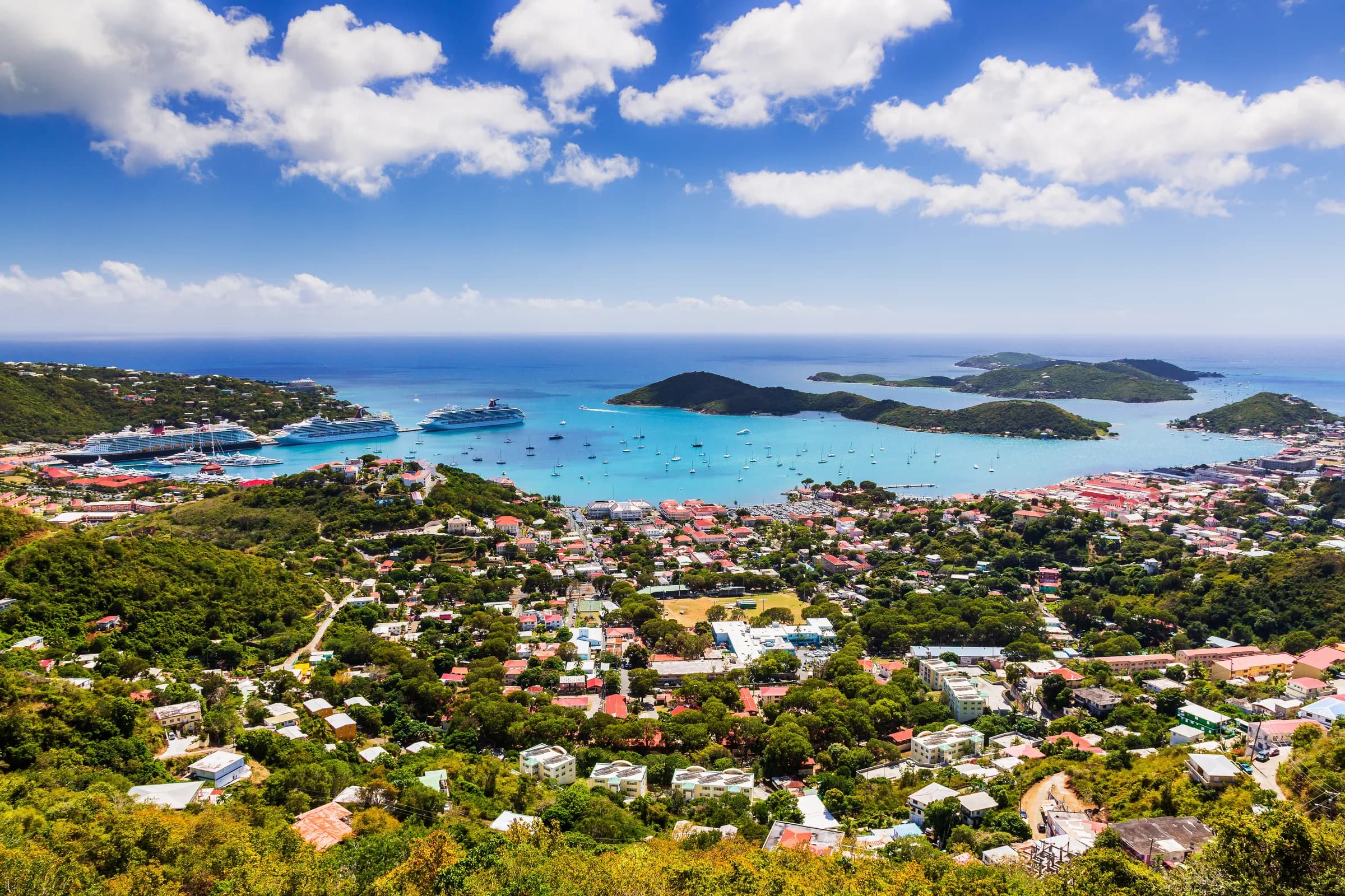 Elevated view over Charlotte Amalie and its harbor on St. Thomas with red roofs, a docked cruise ship, and offshore cays