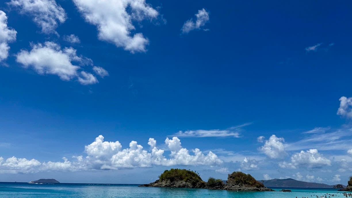Swimmers in clear turquoise water beneath a broad blue sky at Trunk Bay on St. John.