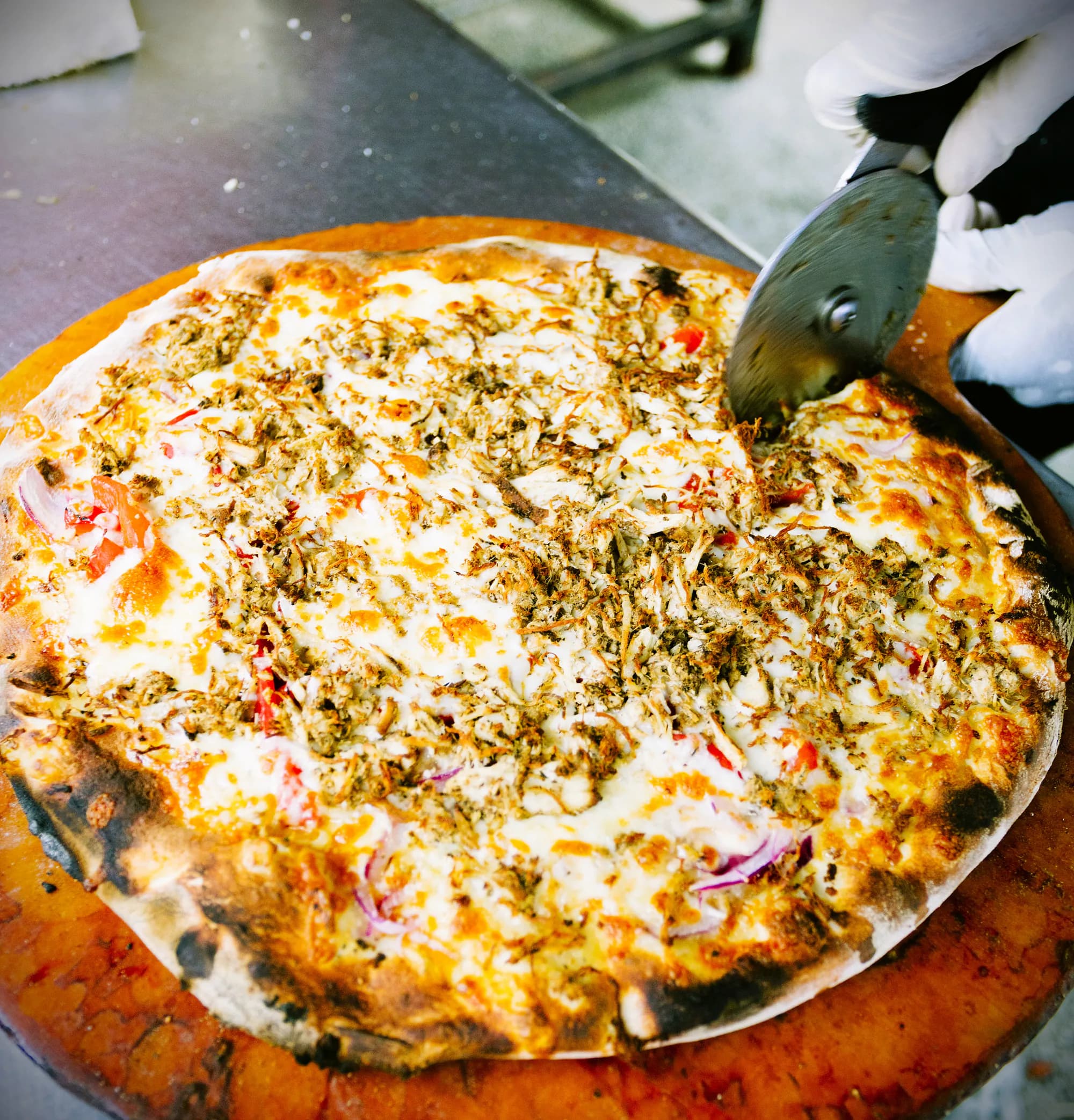 A finished brick-oven pizza being sliced at The Mill.